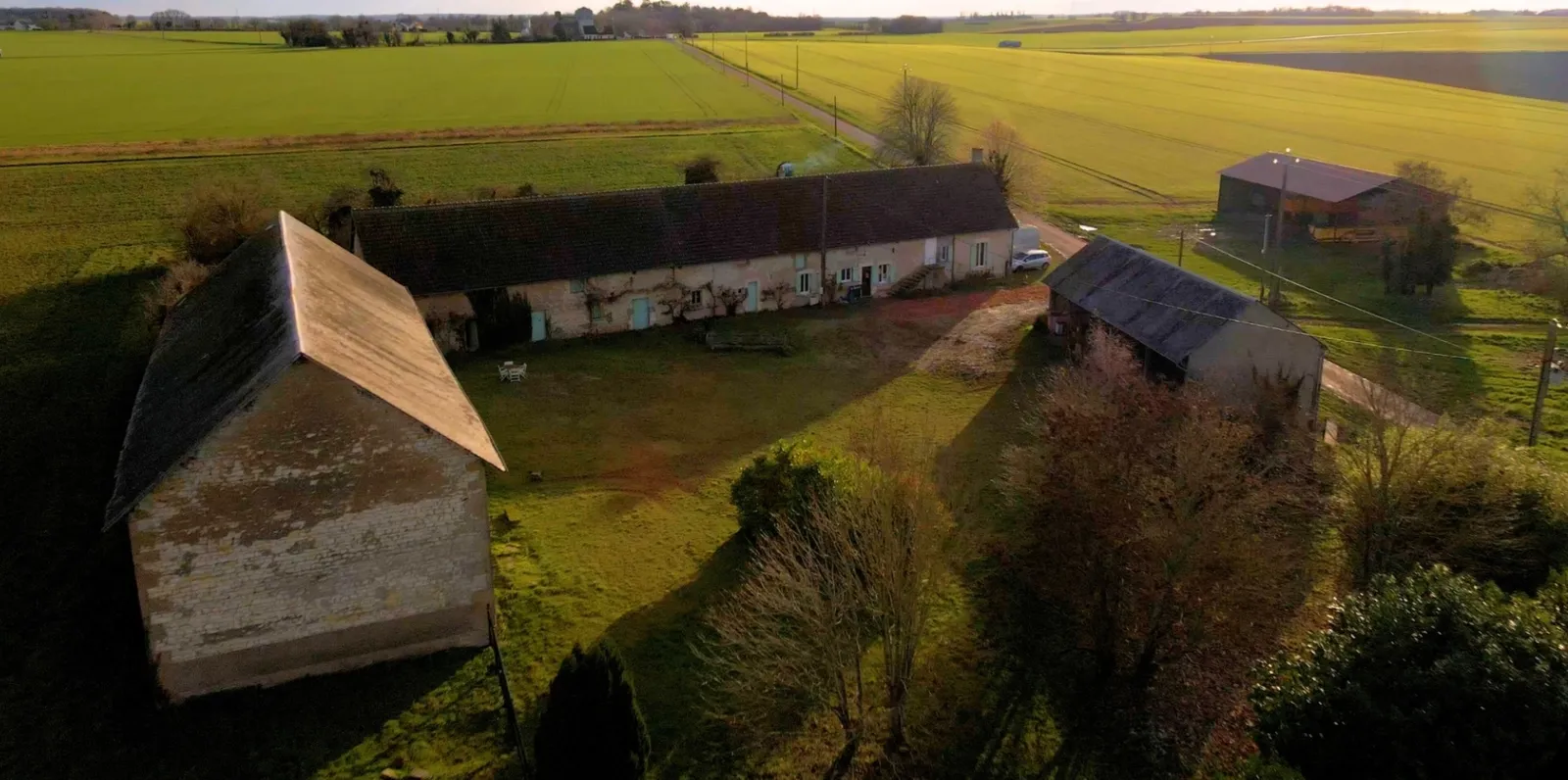 La ferme de La Bernière vue du ciel : les longères de pierre, la cour, les haies et les champs jusqu'à l'horizon.